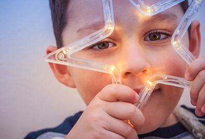 Close-up portrait of boy holding illuminated star shape