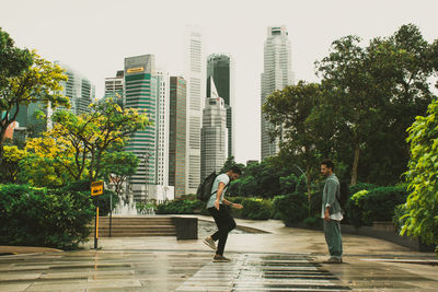 Rear view of woman standing on footpath in city