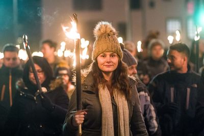 Portrait of young woman standing in city at night