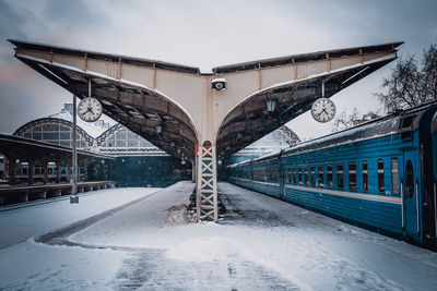 Snow covered railroad tracks against sky during winter