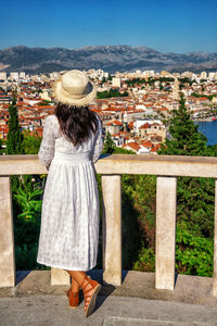 Rear view of woman standing against buildings in city