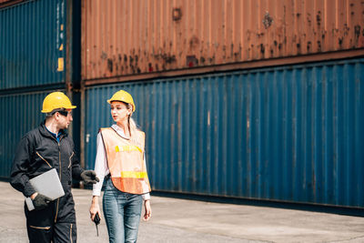 People working with arms raised standing against clear sky