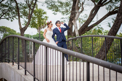 Couple standing by railing against trees