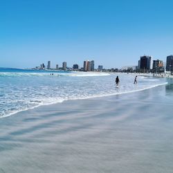 Scenic view of people at beach against clear sky