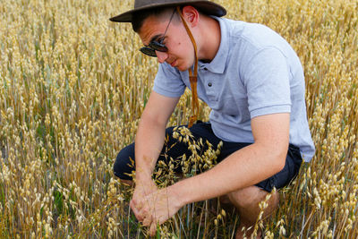 Crop grain. portrait of farmer seating in gold wheat field with blue sky in background. young man 