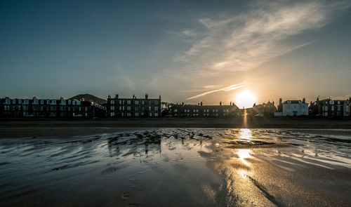 Scenic view of sea and buildings against sky during sunset