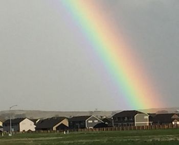 Houses on field against rainbow in sky