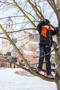 Full length of boy standing on branch during winter