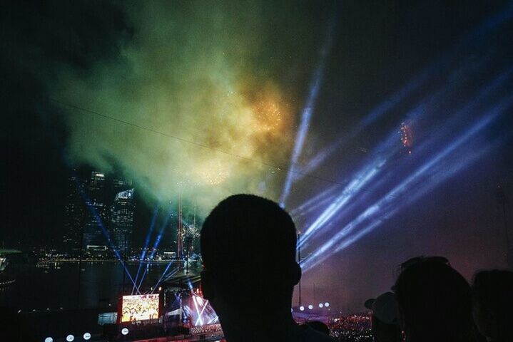 night, illuminated, silhouette, sky, lifestyles, arts culture and entertainment, men, leisure activity, lighting equipment, long exposure, event, light - natural phenomenon, nightlife, low angle view, rear view, light beam, unrecognizable person, dark