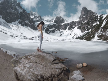 Woman standing on rock against mountains during winter