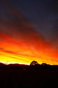 Silhouette landscape against dramatic sky during sunset