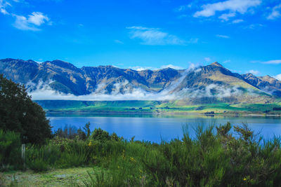 Scenic view of lake and mountains against blue sky