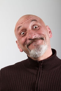 Close-up portrait of happy mature man making face against gray background