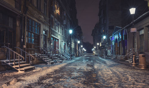 Illuminated street amidst buildings at night