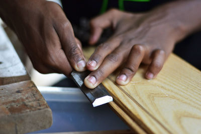 Cropped hands of carpenter planing plank at workshop