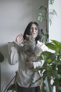 Portrait of young woman standing by plants