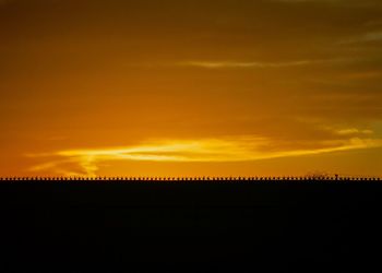 Scenic view of silhouette landscape against orange sky