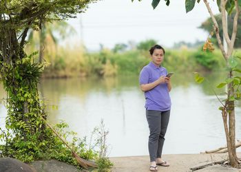 Portrait of woman using mobile phone at lakeshore