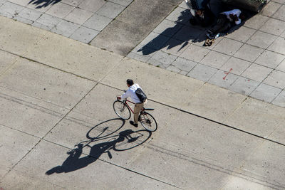 High angle view of men riding bicycle on footpath in city