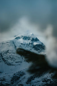 Low angle view of snow covered mountain against cloudy sky