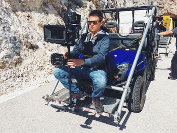 Portrait of man sitting on cart with video camera