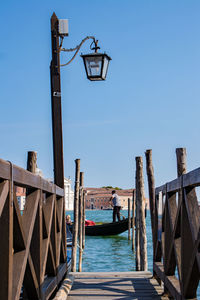 Wooden posts on pier over sea against clear blue sky