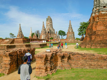 Tourists at temple outside building against sky