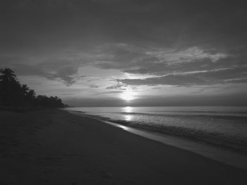 Scenic view of beach against sky at sunset