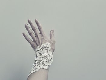 Cropped image of woman hand with macrame bracelet against white wall