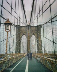 Rear view of people walking on suspension bridge