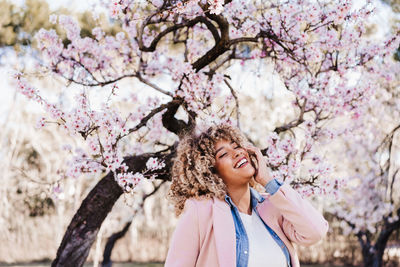 Side view of young woman standing against trees