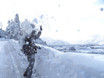 Rear view of person on snowcapped mountain during winter