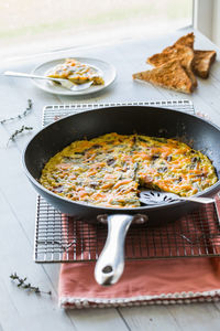 A frying pan holding a bacon and asparagus frittata ready for serving.