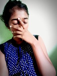 Portrait of beautiful young woman against wall