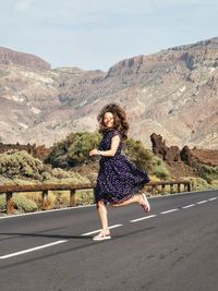 Full length portrait of woman on road against mountain