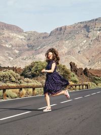 Full length of woman running on road against mountain