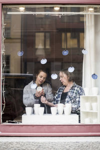 Female potters looking at ceramics container at store window