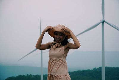 Portrait of young woman standing against sky