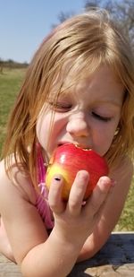 Close-up of girl eating apple outdoors