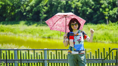 Full length of man holding umbrella standing on sunny day