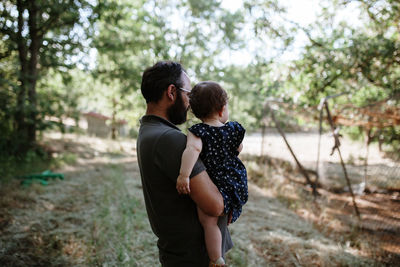 Side view of man holding daughter while standing on field