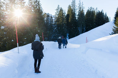 Rear view of walking on snowcapped mountains against blue sky