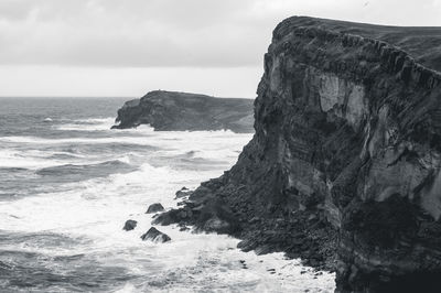 Rock formation on beach against sky