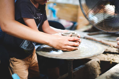 Midsection of people working on pottery wheel