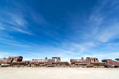 Low angle view of blue sky over old abandoned train at cemetery