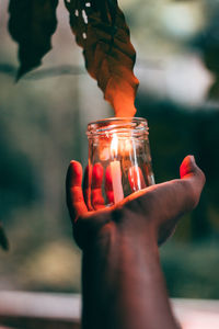 Close-up of hand holding burning candle