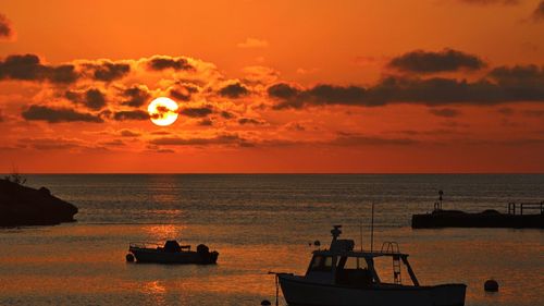 Silhouette boat sailing in sea against sky during sunset