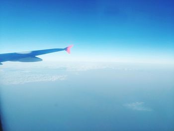 Airplane flying over sea against blue sky