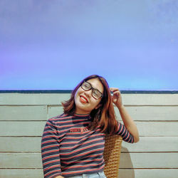 Portrait of smiling young woman standing against sky