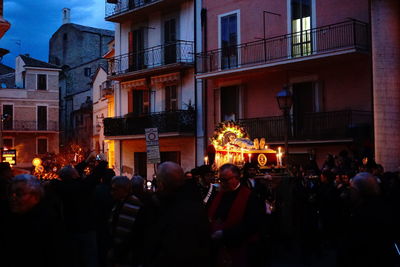 People on street against buildings at night